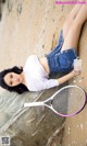 A woman laying on a rock with a tennis racket.