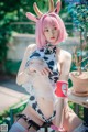 A woman with pink hair wearing a cow costume.