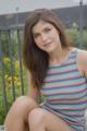 A young woman sitting on a bench in a striped tank top.