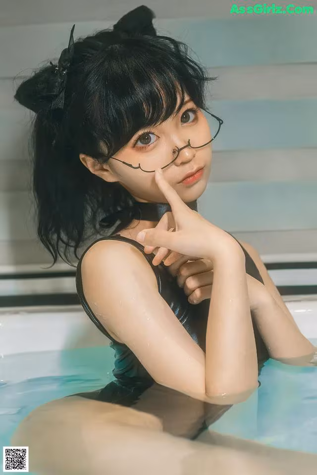 A woman in a black bathing suit sitting in a bathtub.