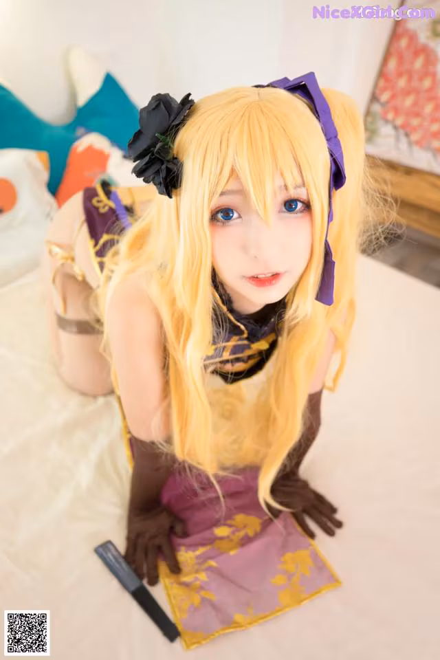 A woman with long blonde hair sitting on a bed.