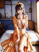 A woman in an orange kimono sitting on a bed.