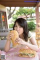 A woman sitting at a table eating a sandwich.