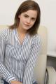 A woman sitting in a chair wearing a blue and white striped shirt.