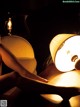 A woman sitting on a couch next to a lamp.