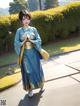 A woman in a blue kimono walking down a sidewalk.