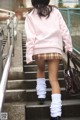 A woman in a pink sweater and plaid skirt is walking up some stairs.