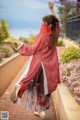 A woman in a red kimono is dancing on a brick walkway.