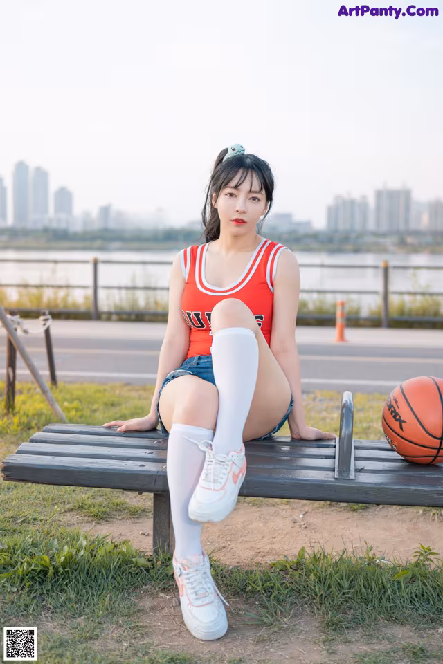 A woman sitting on a bench with a basketball.