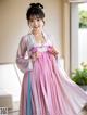 A woman in a pink and blue hanbok is posing for a picture.