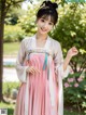 A woman in a pink and white hanbok is posing for a picture.