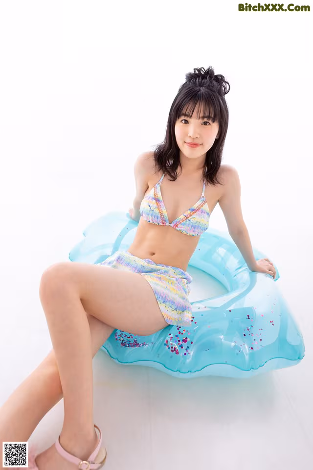 A woman in a bikini sitting on an inflatable pool float.