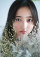 A woman with long black hair holding a bunch of flowers.