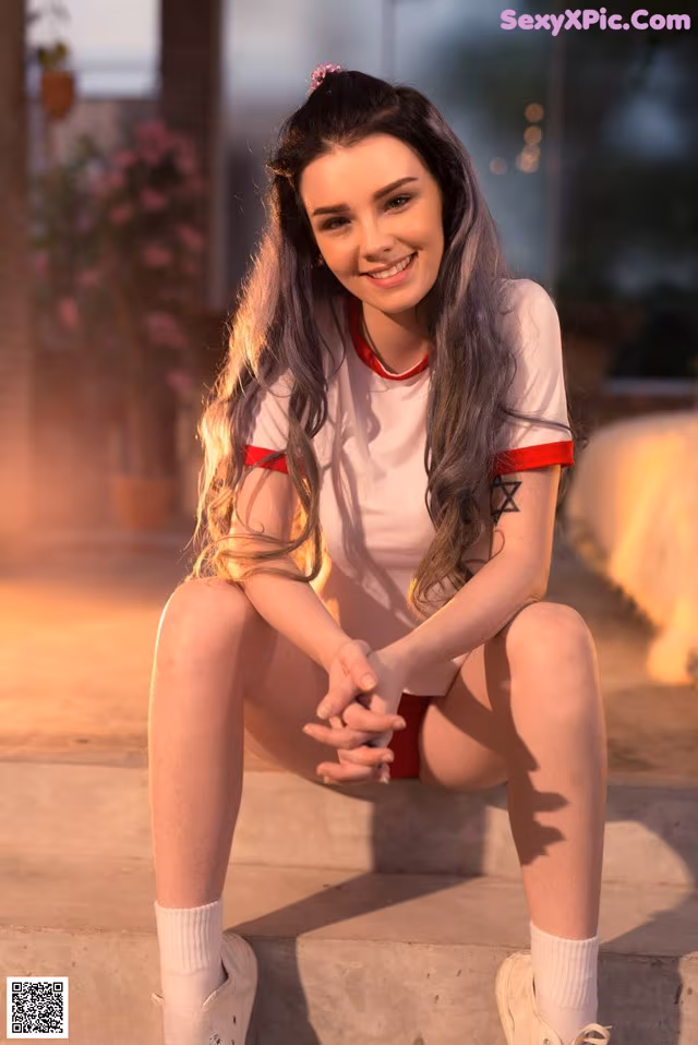 A young woman sitting on the steps of a building.