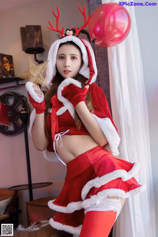 A woman dressed as a santa claus holding a star and a balloon.