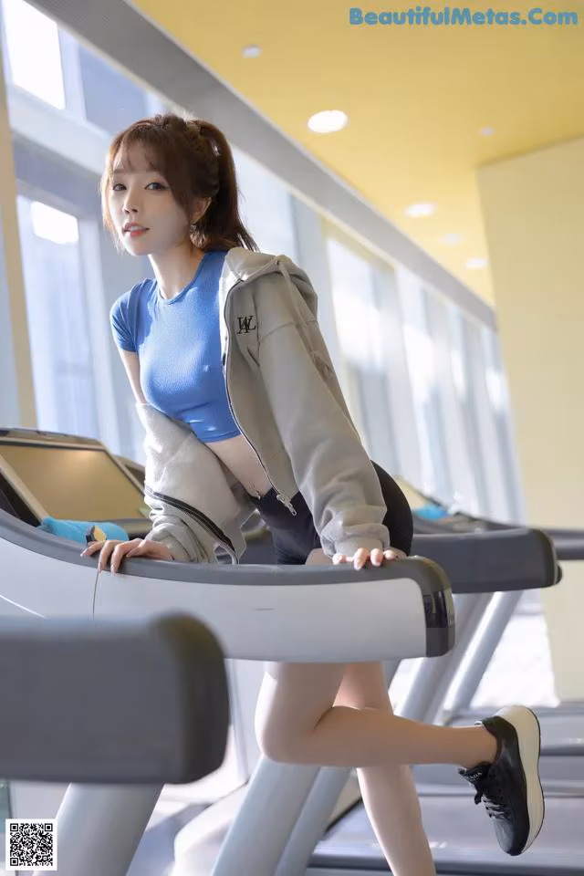 A woman is running on a treadmill in a gym.