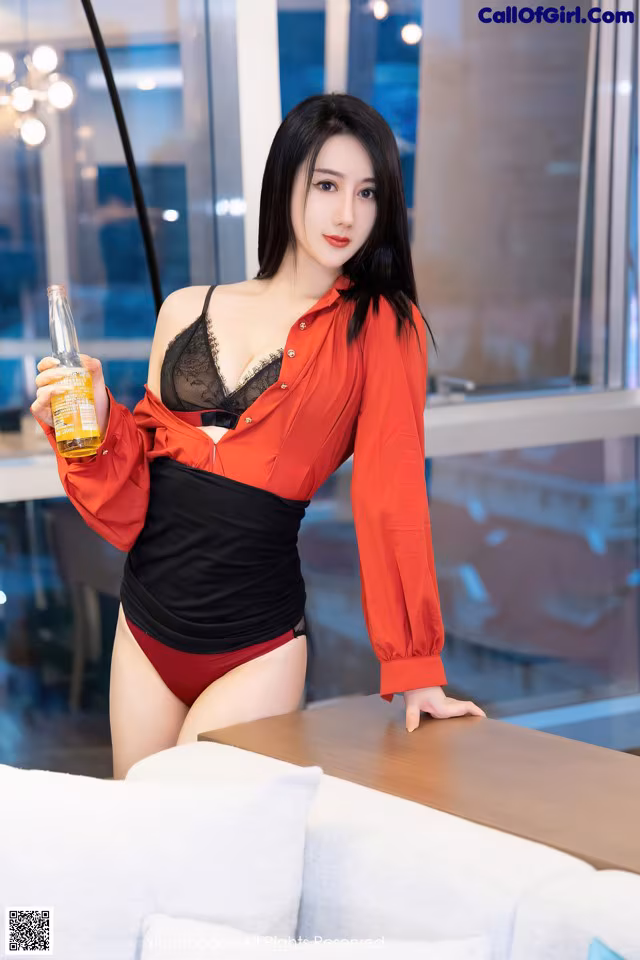 A woman in a red shirt and black lingerie holding a bottle of beer.