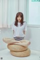 A woman sitting on top of a wicker stool in a room.