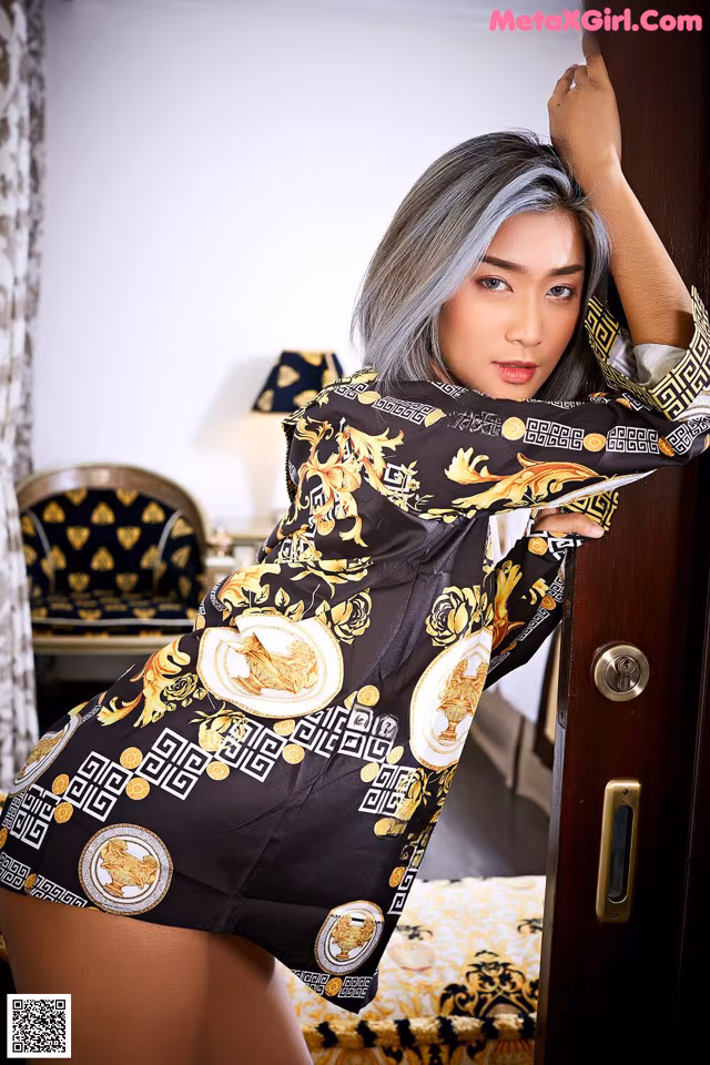 A woman in a black and gold dress leaning against a door.