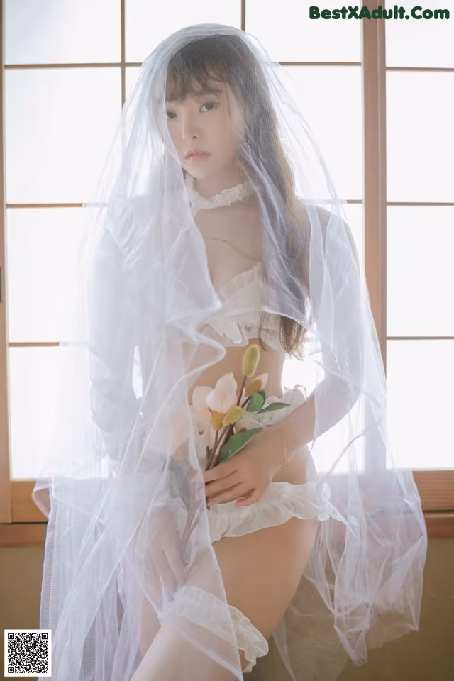 A woman in a white lingerie holding a bouquet of flowers.